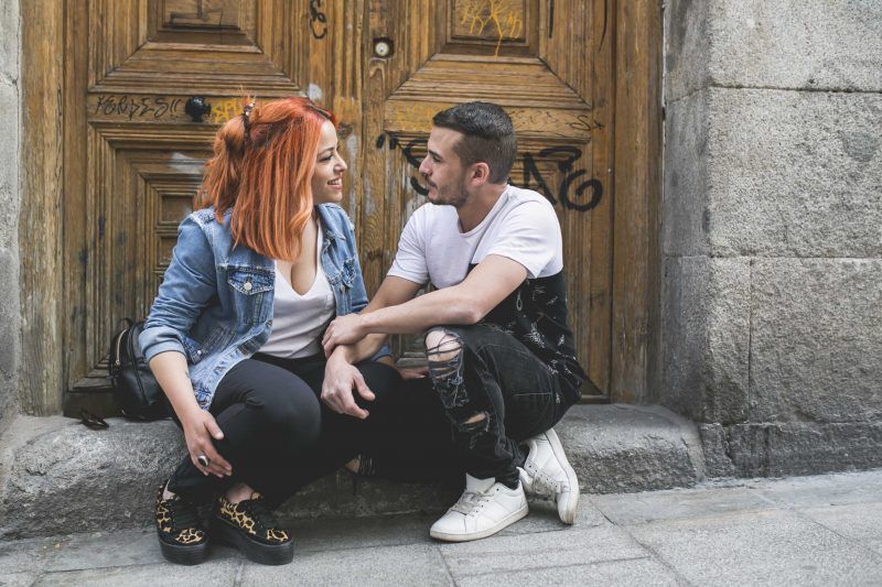 retrato fotográfico. Una pareja sentada en un bordillo se miran a los ojos