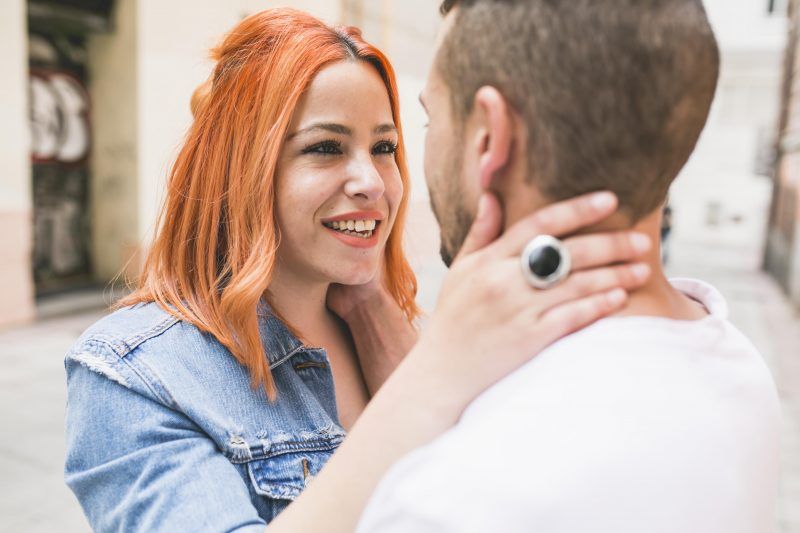 Retrato. Mujer sonriente abraza por el cuello a un hombre