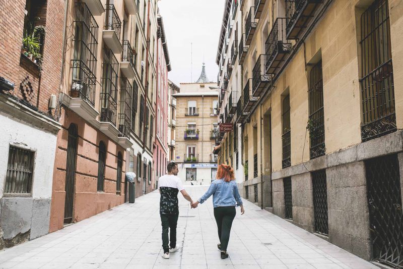 Plano general de una calle por cuyo centro camina de espaldas una pareja