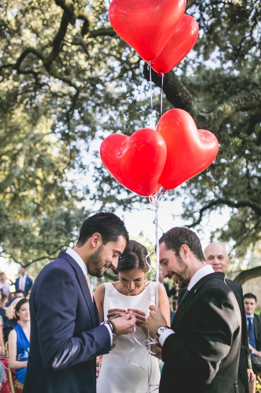 Los novios están colocando unas llaves en unos globos de helio con forma de corazón